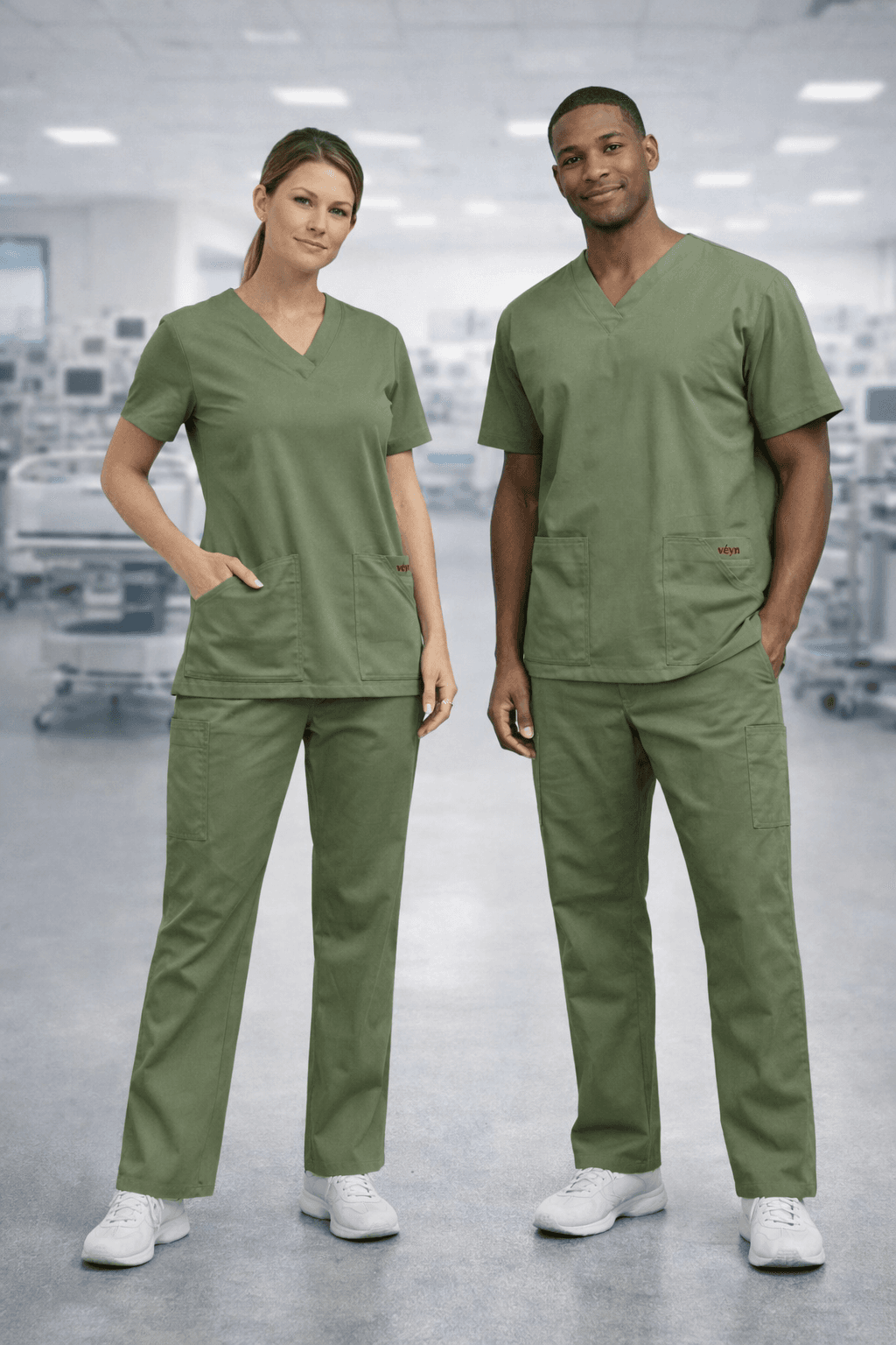 Male and female healthcare workers wearing olive green medical scrubs in a blurred hospital.