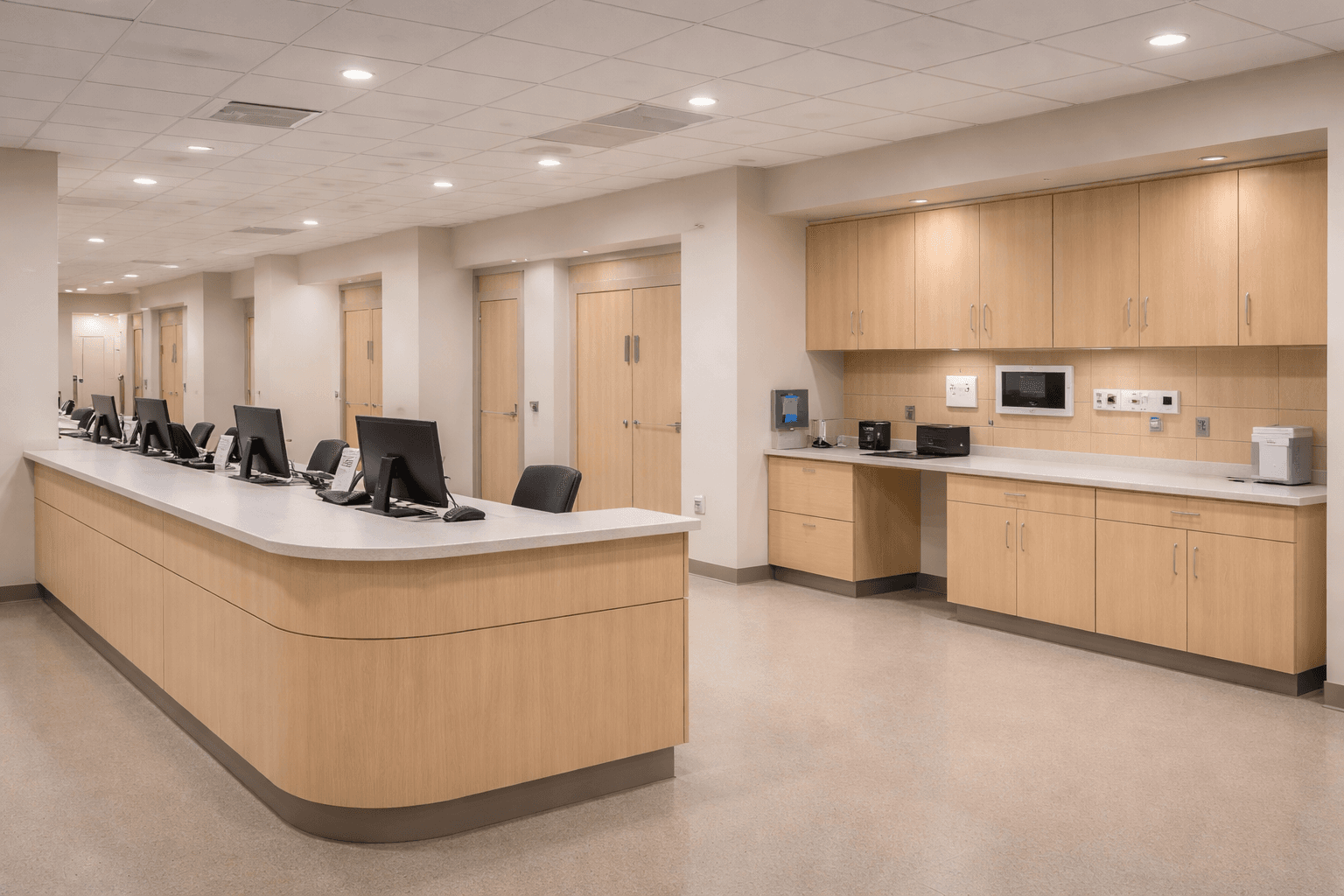 Bright healthcare reception area with a curved wooden desk, computer monitors, and built-in cabinetry.